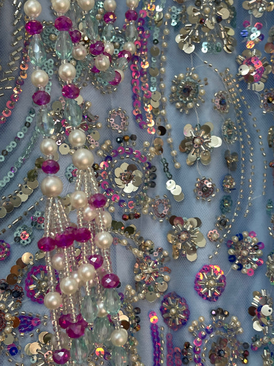 Close-up of a fabric with sequins, beads, and pearls on a blue background