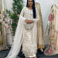 Woman in an embroidered traditional outfit standing in front of a mirror with floral decorations.