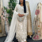 Woman in an ornate white dress standing in front of a mirror with floral decorations.