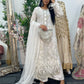 Woman in an embroidered traditional outfit standing in front of a mirror with floral decorations.