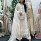 Woman in a white embroidered dress standing in front of a mirror with floral decorations.