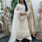 Woman in a white embroidered dress standing in front of a mirror with floral decorations.